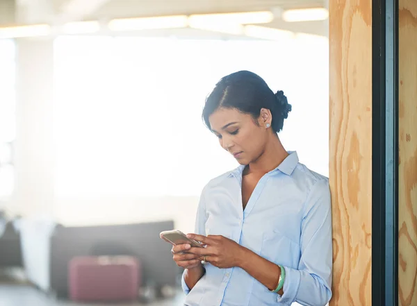 stock image Focused on her schedule. a young woman using her cellphone while standing in an office