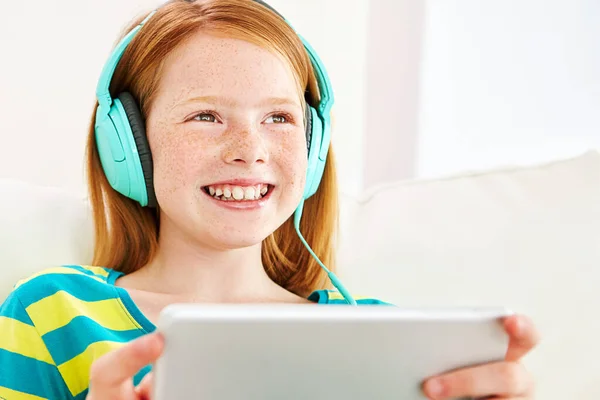 stock image Growing her mind with modern technology. a little girl using a digital tablet with headphones at home