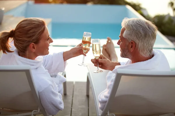 スタイルで彼らの愛を祝う 夕暮れ時にデッキチェアでリラックスしながら 成熟したカップルの飲酒シャンパンのレビューショット — ストック写真