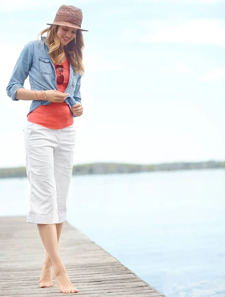 stock image This is where I go to think...A happy young woman standing on a pier next to a lake