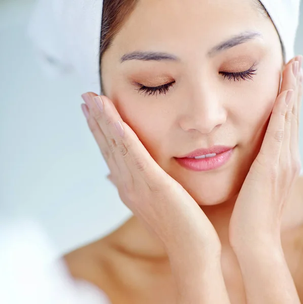 stock image Naturally flawless. A beautiful young Asian woman touching cheeks while wearing a towel on her hand