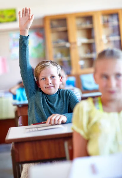 彼は質問がある クラスに座っている間に質問をするために手を上げている若い男の子 — ストック写真
