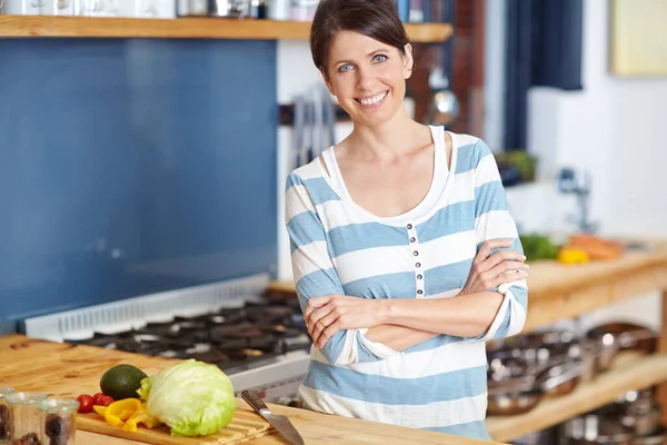 stock image Her family loves her food. Portrait of an attractive woman standing behind a kitchen counter filled with vegetables