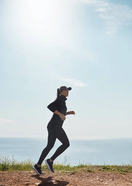 今彼女を止めることはできない 海を背景に一人でジョギングをする若い女性が — ストック写真
