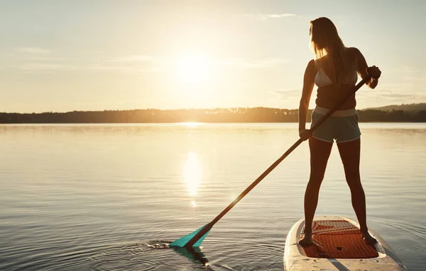 水の静けさが彼女を落ち着かせる 魅力的な若い女性のパドルボートが湖に乗り — ストック写真