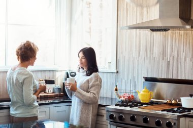 Annem hala en iyi hikayeleri anlatıyor. Kahve molası verip mutfakta annesiyle sohbet eden genç bir kadın.