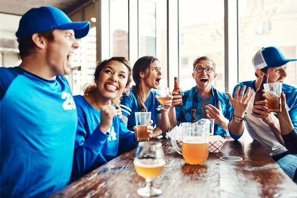 Sport has the unique power to unite people. a group of friends having beers while watching a sports game at a bar