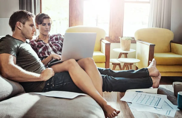 stock image Great financial planning afforded them this comfortable lifestyle. a young couple using a laptop and going through paperwork together on the sofa at home