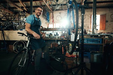 Tüm bisiklet ihtiyaçlarınızı karşılamama izin verin. Bisiklet tamirhanesinde çalışan olgun bir adamın portresi.