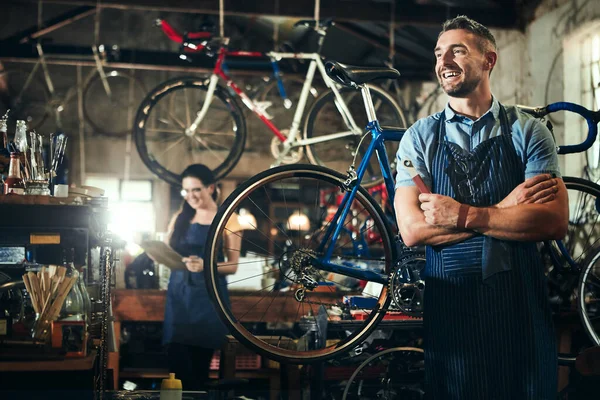 Running a successful bicycle repair shop. a mature man working in a bicycle repair shop with his coworker in the background