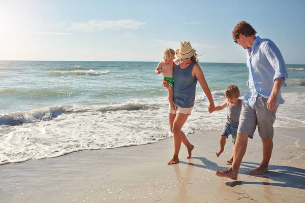 海の水に彼の最初の一歩を踏み出す ビーチで夏の日を楽しむ若い家族が — ストック写真