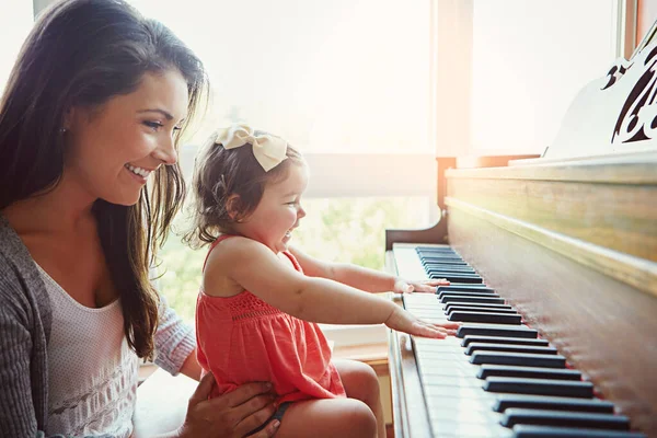 Piano lessons with Mom are always fun. a mother watching her adorable little daughter playing the piano at home
