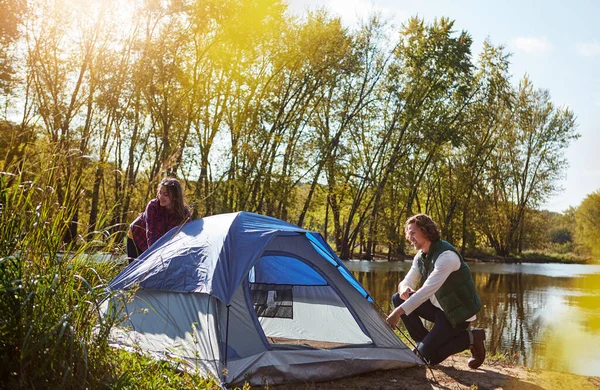 stock image Home is where you pitch your tent. an adventurous setting up their tent by the lake