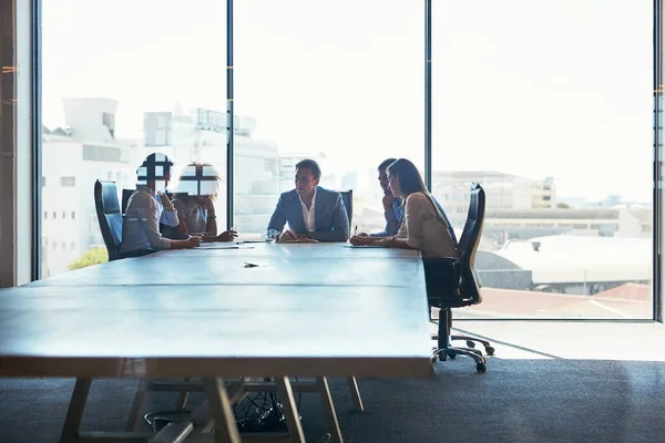 Going over their plan of action in the boardroom. Full length shot of a group of businesspeople meeting in the boardroom