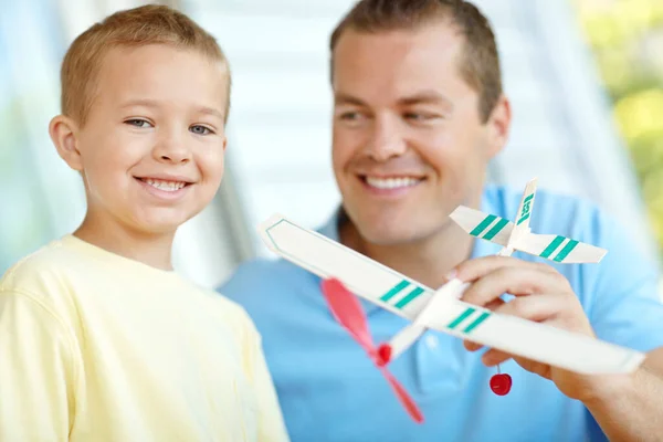 彼の息子に飛行機の操縦方法を教える 父親と一緒にカメラで笑顔を浮かべおもちゃの飛行機を持っていた — ストック写真