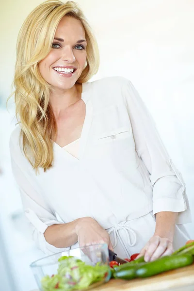 Stock image Eating and cooking healthily. Attractive young blonde woman smiling while chopping fresh vegetables at home