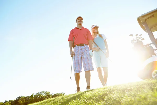 ゴルフは充実したスポーツです 緑の魅力的なゴルフカップルとともに太陽が彼らの後ろに沈む — ストック写真