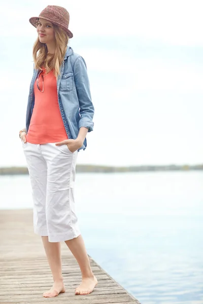 Stock image Lost in a peaceful moment. A happy young woman standing on a pier next to a lake