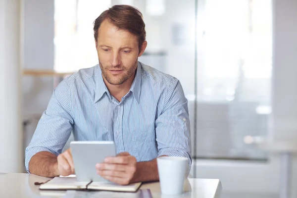 stock image Focused on the task at hand. a mature businssman using a digital tablet at his desk in the office