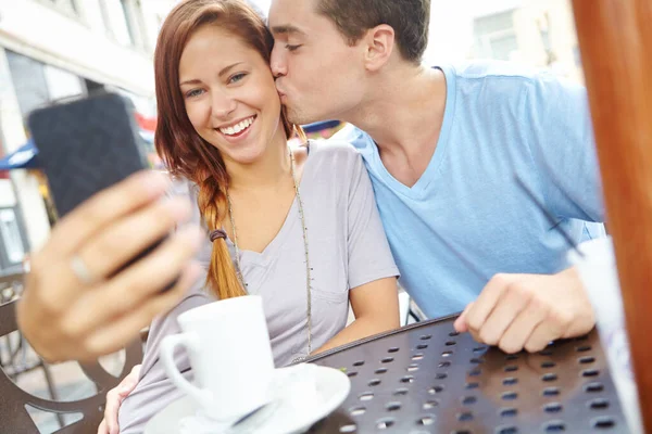 彼らの幸せな記憶を捉える 幸せなカップルがカフェに座って携帯電話で自分自身の写真を撮る — ストック写真