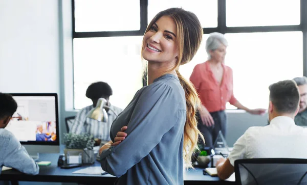 The right mindset to keep a team motivated. Portrait of a confident young businesswoman working in a modern office with her colleagues in the background