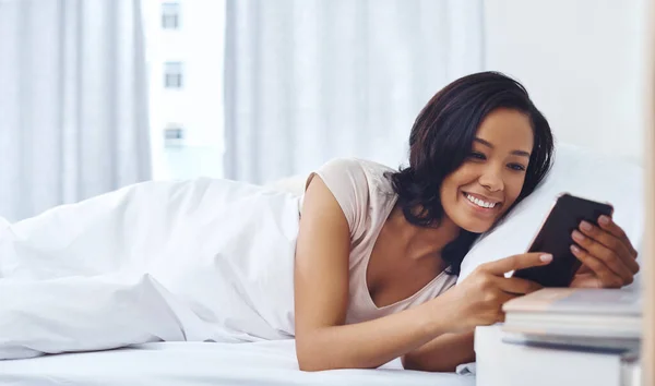 Stock image First browsing session for the day. a young woman waking up in the morning and using her phone in bed