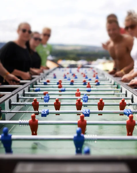 Friends playing with a foosball at a party for competition, fun skill or sports event. Celebration, activity and group of people enjoying a football table game or match for a friendly championship