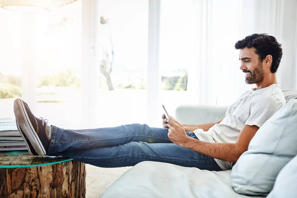 stock image Downtime with a digital tablet. a man using a digital tablet and relaxing on the sofa at home