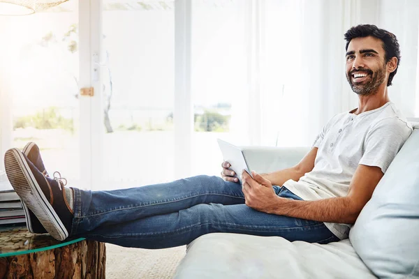 一个很酷的新系列的流媒体节目 一个在家里用数码平板电脑在沙发上放松的男人 — 图库照片