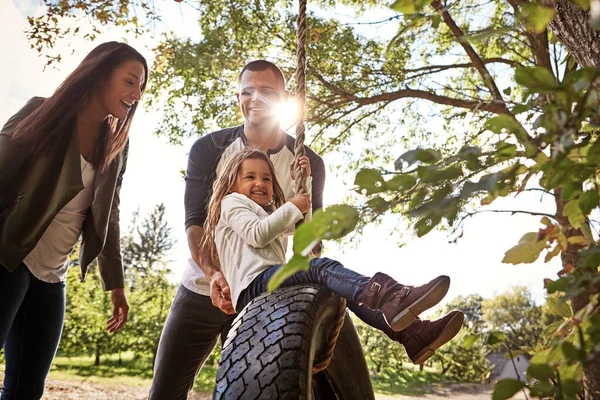 Making time for the people that matter most. a happy mother and father pushing their daughter on a tyre swing