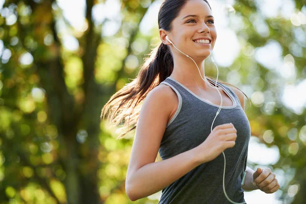 耳机和妇女在公园里跑步是为了健康 健康和户外运动 体育和女运动员跑步者在花园里做有氧运动 同时听音乐和训练 — 图库照片