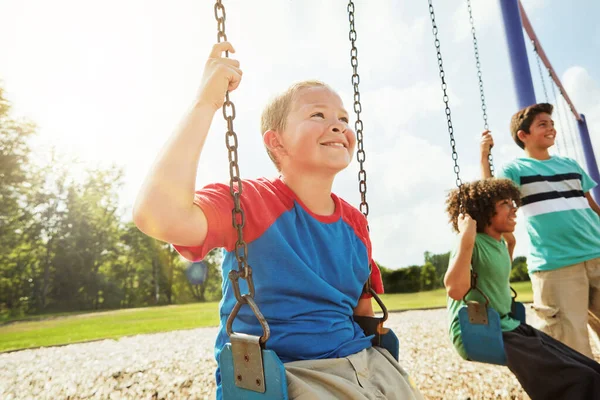 屋外無料プレイは子供にとって有益です 公園でブランコに乗って遊ぶ少年たち — ストック写真