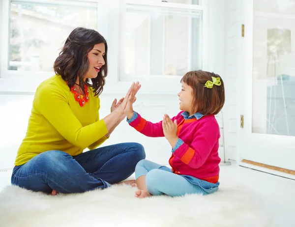Its all fun and games with Mom. an adorable little girl playing a clapping game with her mother at home