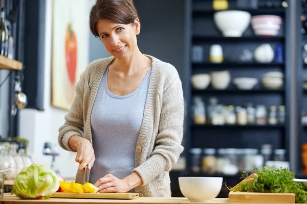 Making sure her family eats healthy. an attractive woman chopping vegetables at a kitchen counter