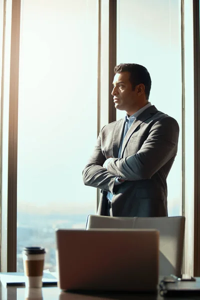 stock image Confidence got him to the top. a handsome young businessman standing with his arms folded in the office