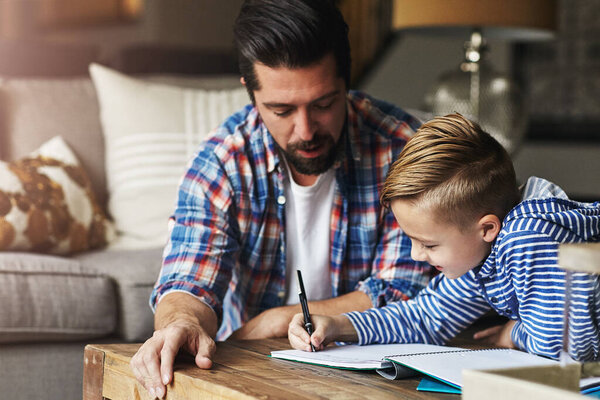 Dads always around to help out. a father helping his little son with his homework