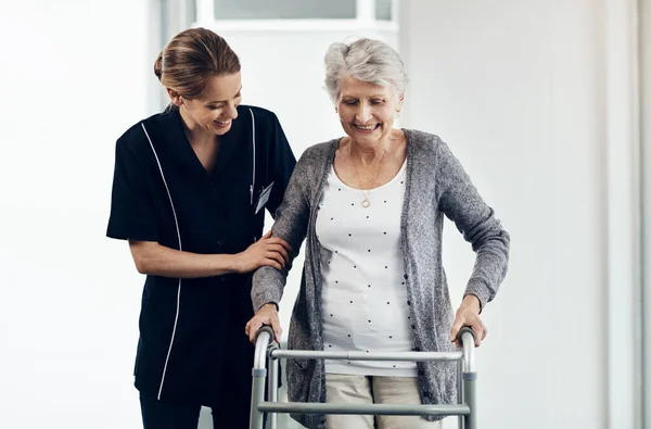 stock image She lets me to go at my own pace. a female nurse assisting a senior woman using a walker