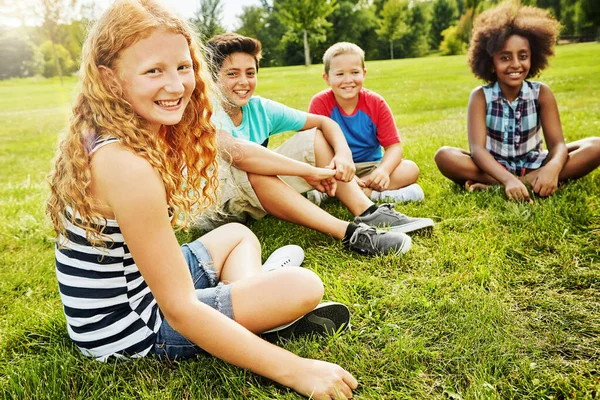 友達といるといつも草が緑になります 外の草の上に座っている多様で幸せな子供たちのグループの肖像画 — ストック写真