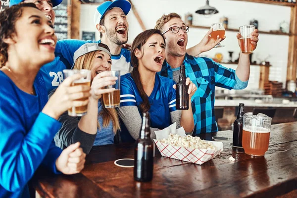 stock image Getting swept up in the atmosphere of game day. a group of friends having beers while watching a sports game at a bar