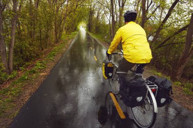 Gidiyor, gidiyor, gitti. Erkek bir bisikletçinin ıslak bir kış sabahı bisiklet sürerken çekilmiş dikiz görüntüsü.