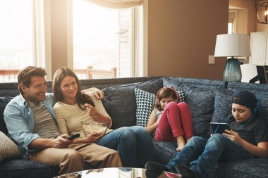 Her biri kendi eğlencesini tercih ediyor. Çocukları evde dijital tablet kullanmakla meşgulken bir çift televizyon izliyor.