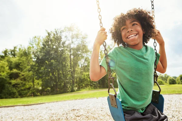 子供の頃のシンプルな喜び 公園でブランコに乗って遊んでいる少年が — ストック写真