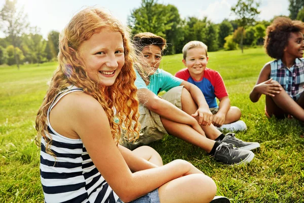 楽しい時間についてのすべて一緒に 外の草の上に座っている多様で幸せな子供たちのグループの肖像画 — ストック写真