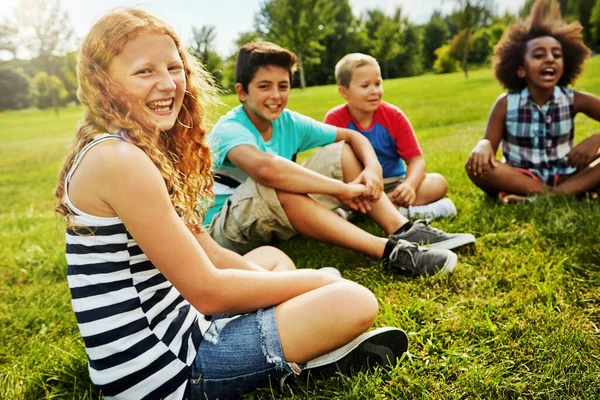 祝您在好友中度过一个阳光灿烂的日子 一群多姿多彩快乐的孩子坐在外面的草地上的画像 — 图库照片