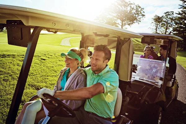 Connecting with other couples out on the course. a group of friends riding in a golf cart on a golf course