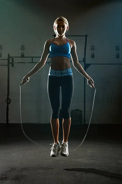 Take action, just jump. a young woman jumping rope in a gym