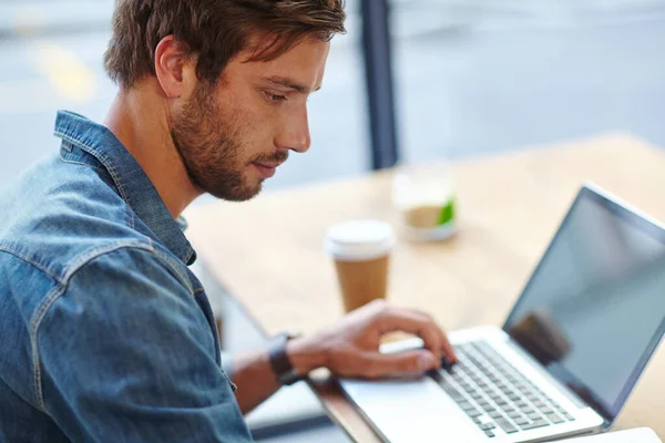 コーヒーが入るのを待っている コーヒーショップでノートパソコンを使っているハンサムな若い男が — ストック写真