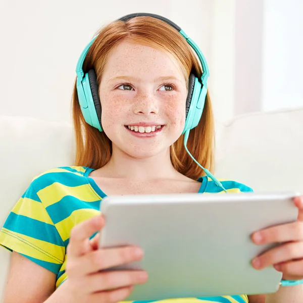 stock image Shes one connected kid. a little girl using a digital tablet with headphones at home