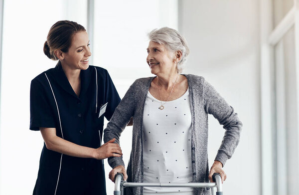 Shes all the care you need. a female nurse assisting a senior woman using a walker