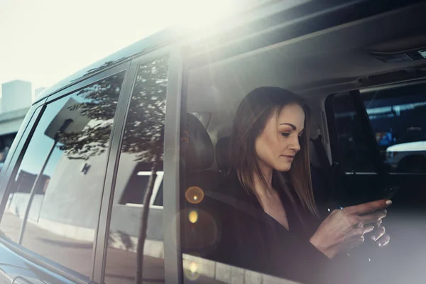 在电话里走来走去在开车旅行时使用手机的年轻女商人 — 图库照片